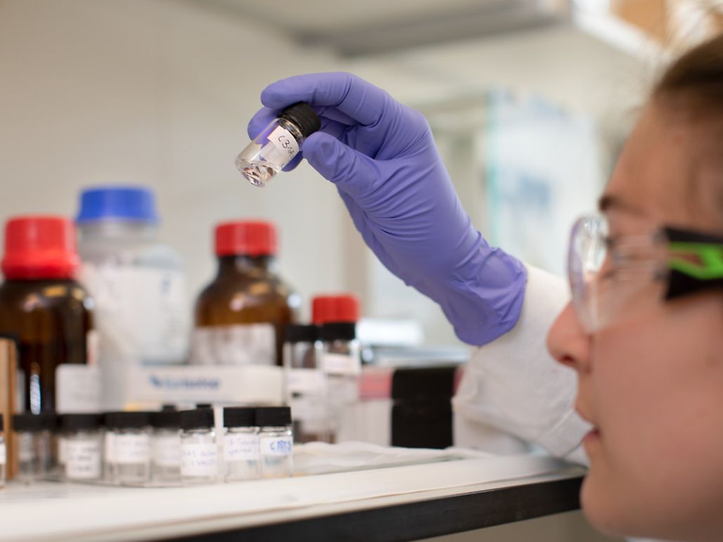 Researcher holding a vial with liquid in a laboratory environment